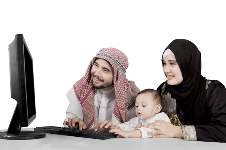 Muslim family using computer isolated over white backgroundの写真素材