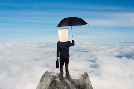 Business concept: Unknown businessman carrying umbrella on top of mountainの写真素材