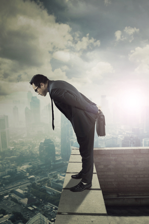 Portrait of Asian businessman standing on the rooftop while looking down at the cityの写真素材