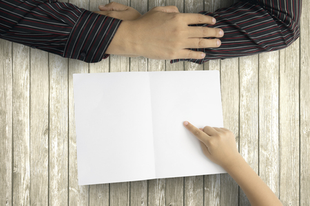 Father's Day. Hands of little child pointing an empty greeting card for his father above a wooden tableの写真素材