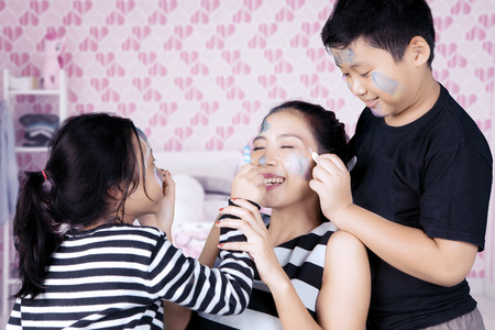 Siblings having time doing face painting to motherの写真素材