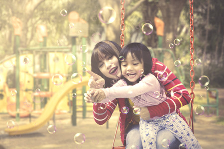 Mother and daughter play soap bubbles at playground. Summer and Spring conceptの写真素材