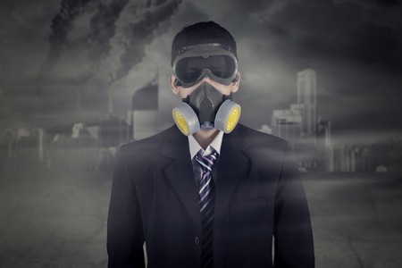 Picture of unknown male worker wearing gas mask while standing in the polluted cityの写真素材