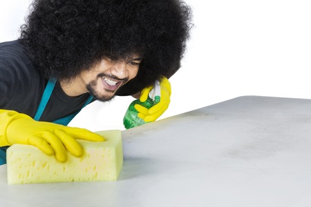 Young cleaning service professional cleaning the desk isolated over whiteの写真素材