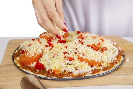 Closeup of an unknown female chef adding grated cheeses on a pizzaの写真素材