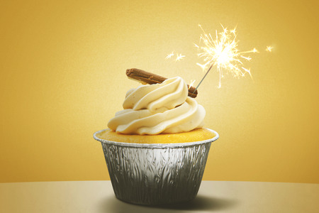 Closeup of delicious cupcake with sparkle on the table. Shot with yellow background