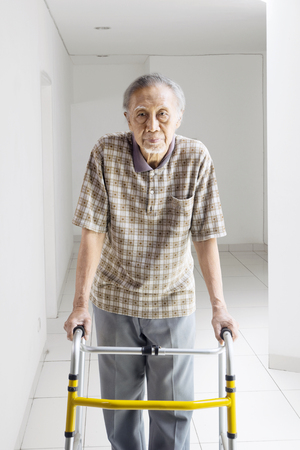 Portrait of lonely Asian elderly man walking with a walker at homeの写真素材