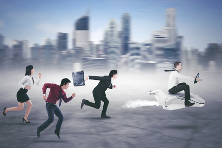 American businessman defeating his rivals in the race while driving a plane with modern city backgroundの写真素材