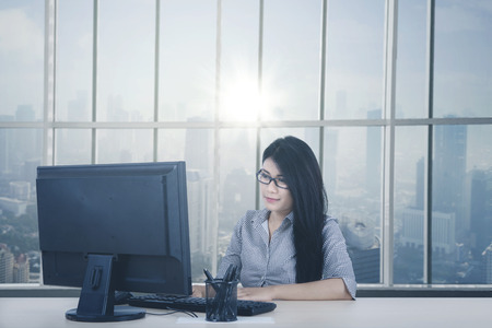 Young businesswoman working with computer while sitting by the window. Shot in the officeの写真素材