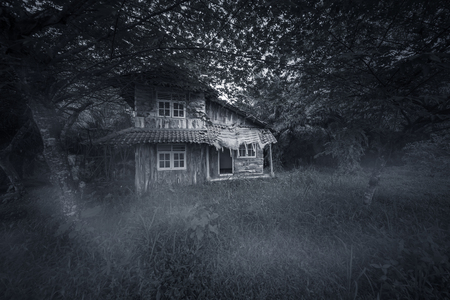 Image of abandoned wood house looks haunted with damaged rooftop. Shot at night timeの写真素材