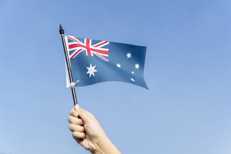 Close up of unknown child hands waving an Australia flag with blue sky of backgroundの写真素材
