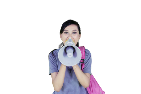 Image of female college student carrying a bag while using a megaphone to speak at the cameraの写真素材