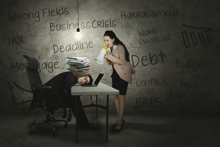 Picture of angry female leader screaming to her exhausted employee through a megaphoneの写真素材