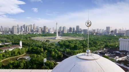 JAKARTA - Indonesia. JULY 24, 2018: Dome of Istiqlal mosque with National Monument and skyscrapers in the backgroundのeditorial素材