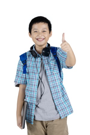Picture of a handsome teen student carrying a laptop while showing his thumb at the camera, isolated on white backgroundの写真素材