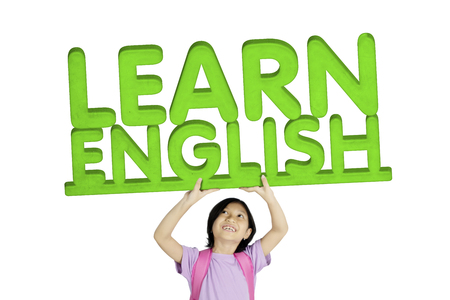 Close up of adorable schoolgirl lifting word of Learn English, isolated on white backgroundの写真素材