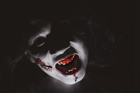 Halloween Horror concept: Closeup portrait of a creepy zombie woman with bloody wound on faceの写真素材