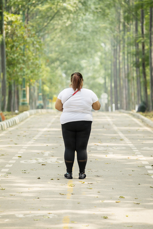 Rear view of young fat woman wearing sportswear while standing on the roadの写真素材