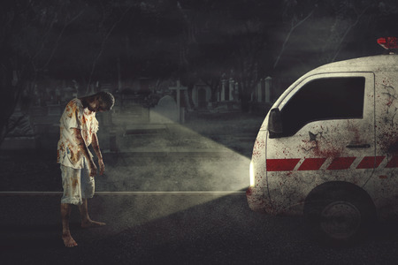 Picture of male ghost stopping an ambulance car while standing with grave backgroundの写真素材