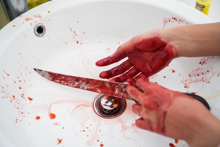 Halloween horror concept. Image of unknown woman hands holding a knife with bloody stain in the sinkの写真素材