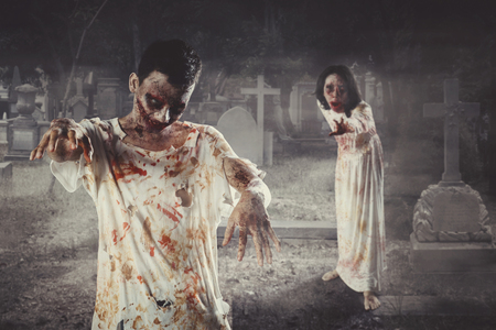 Two scary ghosts standing in the cemetery at night time. Concept of Halloween horrorの写真素材