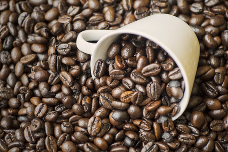Picture of coffee cup on the heap coffee beans over wooden tableの写真素材