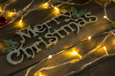 Close up of Christmas lights glowing near a Merry Christmas text on the wooden tableの写真素材