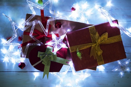Top view of Christmas star lights with a pile of Christmas gifts on the wooden table