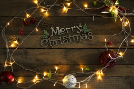 Top view of Merry Christmas text with Christmas lights on the wooden table