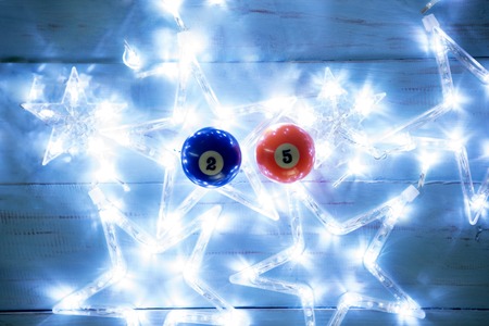 Top view of two billiard balls with Christmas lights shaped stars on the wooden table