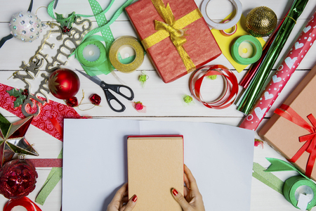 Woman hands packing Christmas gift boxes on the wooden tableの写真素材