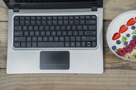 Top view of computer laptop with healthy cereals on the wooden tableの写真素材
