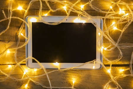High angle view of messy Christmas lights with a digital tablet on the wooden table