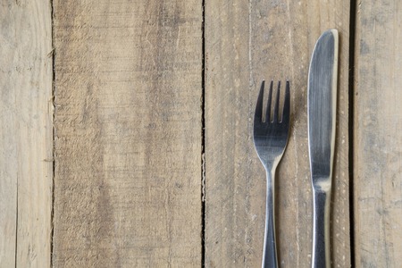 Close up of a silver knife and fork on the wooden tableの写真素材