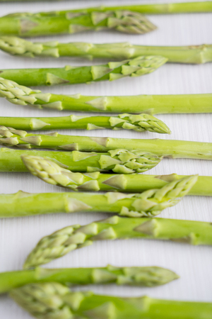 Image of fresh green raw sprouts of asparagus on the wooden table. Shot in the studioの写真素材