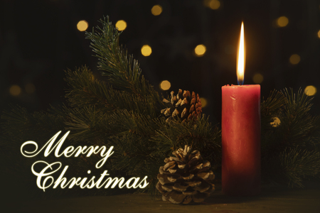 Red candle and pine cone on the table with Merry Christmas text. Shot with blurred sparkling light backgroundの写真素材