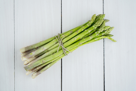 Image of a bunch of fresh green raw asparagus on the wooden table background. Shot in the studioの写真素材