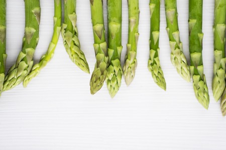 Macro shot of green asparagus buds on the wooden table background. Shot in the studioの写真素材