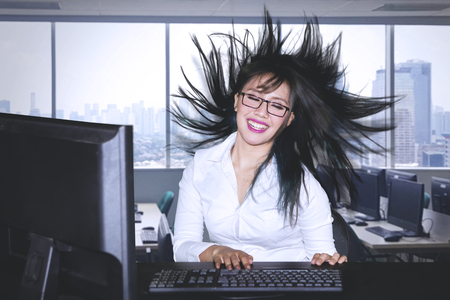 Female entrepreneur looks happy while working in the office with her hair blowingの写真素材