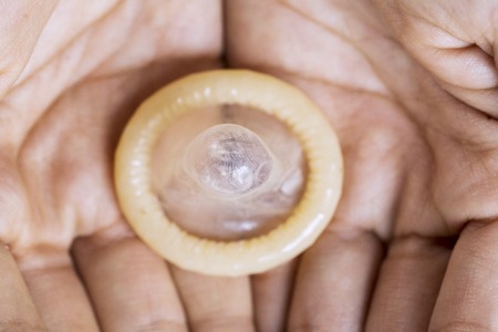 Top view of an unknown man holding a condom on his palmの写真素材