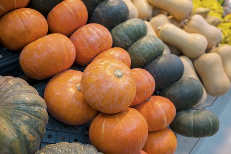 Closeup of pile of green and orange pumpkins in the supermarket