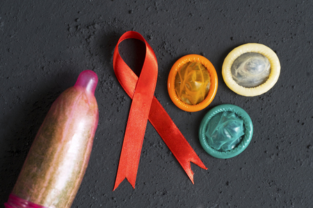Top view of cucumber with condoms and red ribbon over black tableの写真素材