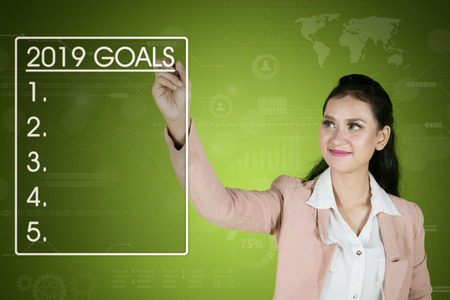 Image of pretty businesswoman writes list goals for 2019 on the virtual screen
