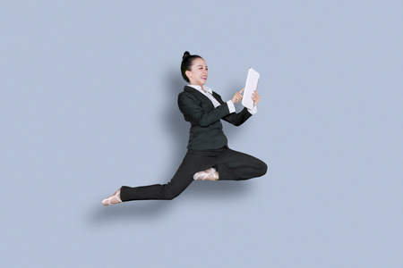 Picture of Asian businesswoman wearing ballet shoes and dancing in the studio while using a digital tabletの写真素材