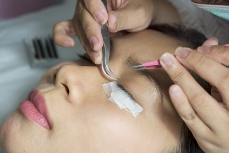 Close up of young woman undergoing eyelash extensions treatment in a beauty salonの写真素材