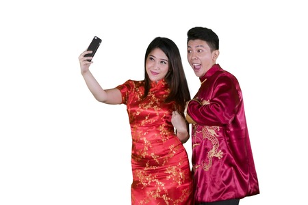 Picture of happy couple taking a selfie photo by using a smartphone while celebrating Chinese new yearの写真素材