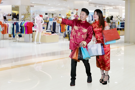Chinese New Year concept. Asian couple pointing something in the mall after buying giftsの写真素材