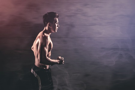 Side view of a sporty young man doing run exercises in the studio