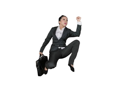 Low angle view of female manager carrying a suitcase while sprinting on the studio, isolated on...