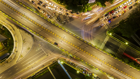 Top view of beautiful crossroads with lights of vehicle at night time in Jakarta city